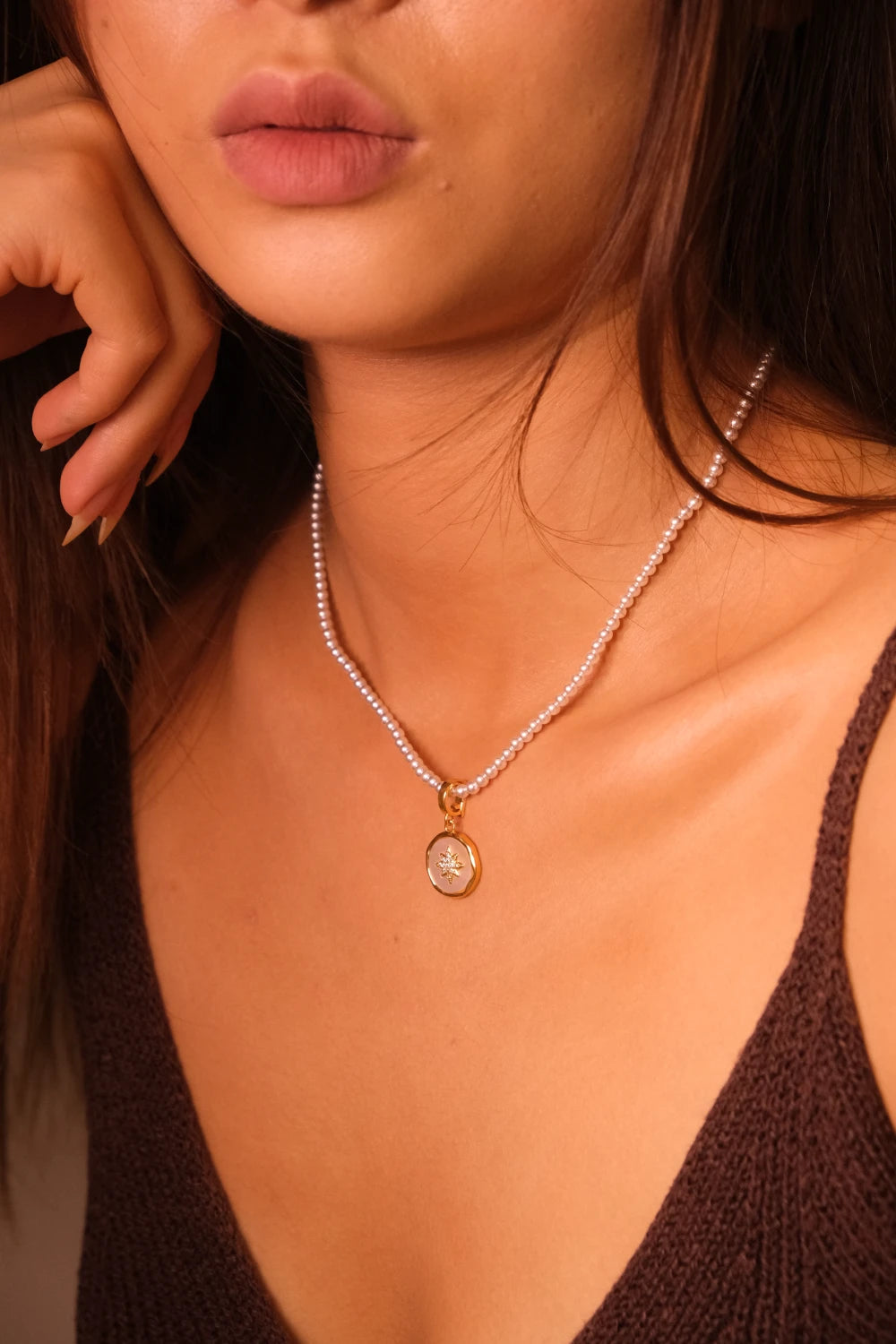 Close-up of a woman wearing a pearl necklace with a pendant.