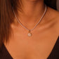 Close-up of a necklace with a pendant on a person wearing a brown top.