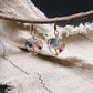 Multi-crystalearrings,  for Vitality & Protection, on a branch with a textured fabric background