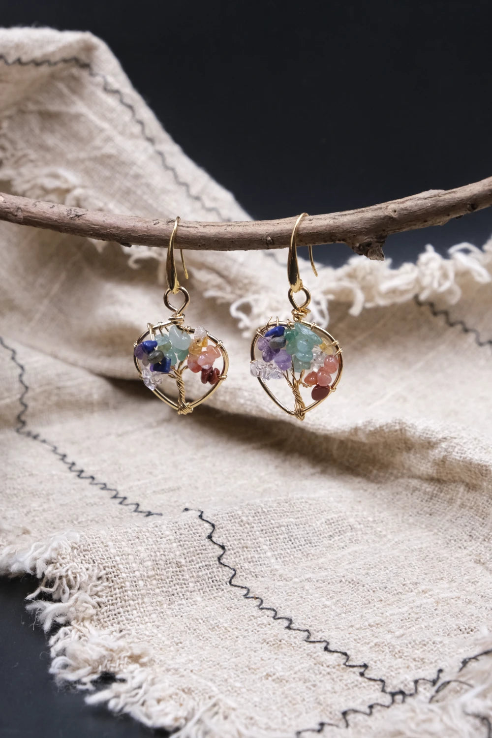 Multi-crystalearrings,  for Vitality & Protection, on a branch with a textured fabric background