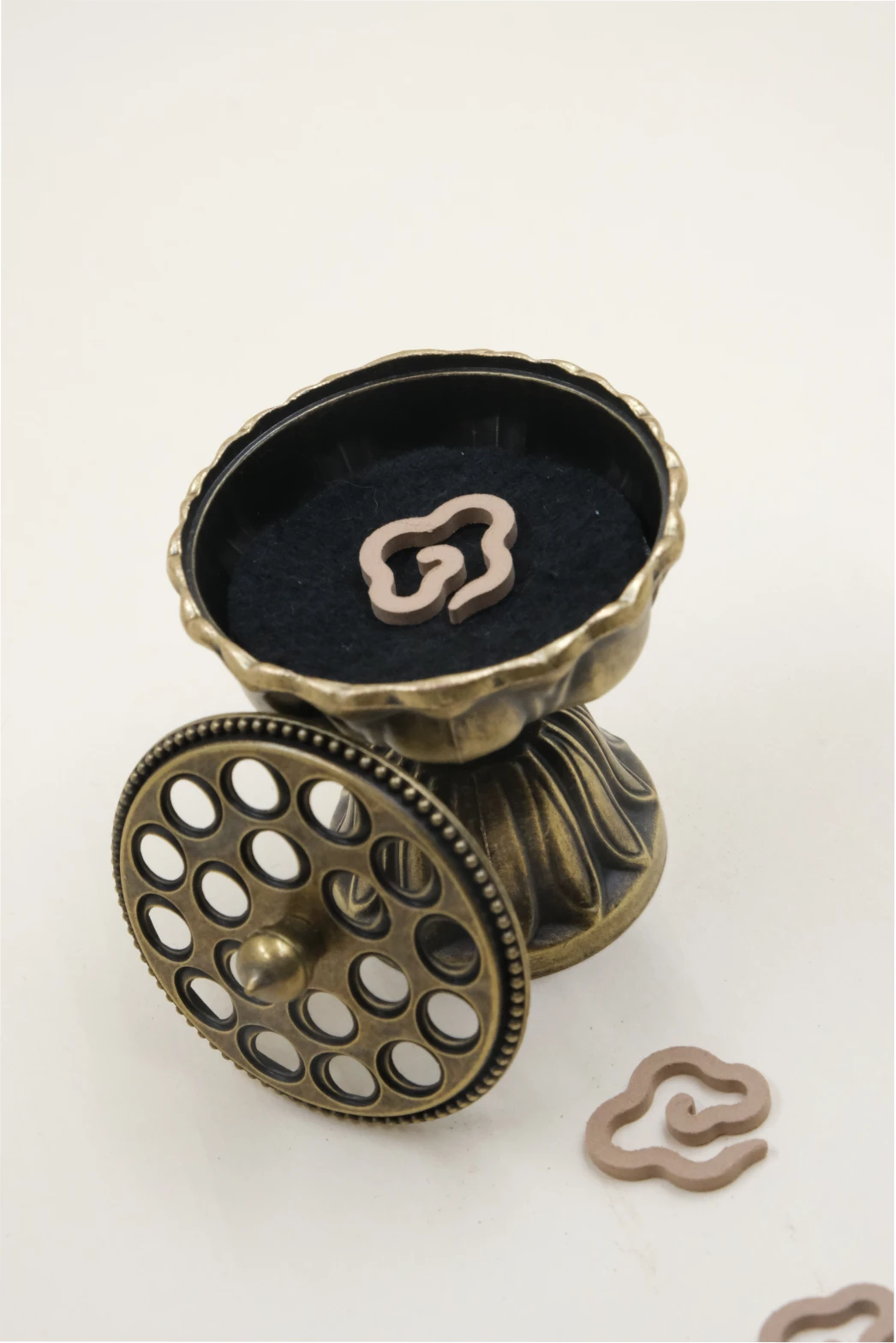 Feng Shui Lotus Pedestal Incense Burner in bronze finish, shown with its lid open to reveal incense chips inside, displayed together with cloud-shaped incense coils.