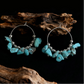 Hoop earrings with turquoise stones and silver beads on a dark background with wooden elements.