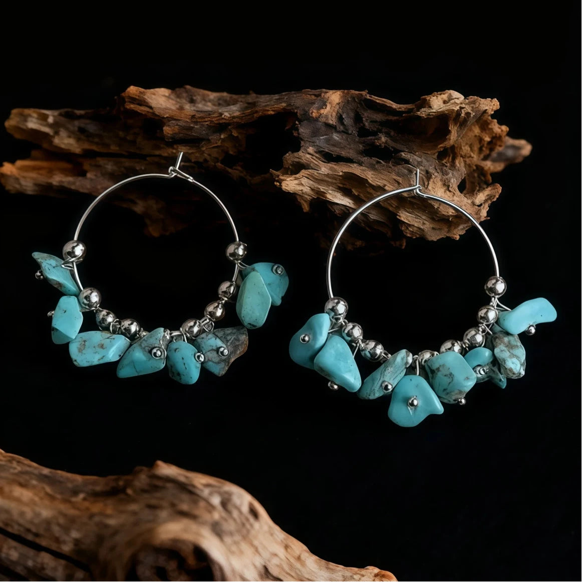 Hoop earrings with turquoise stones and silver beads on a dark background with wooden elements.