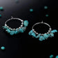 Turquoise hoop earrings with silver beads on a black background