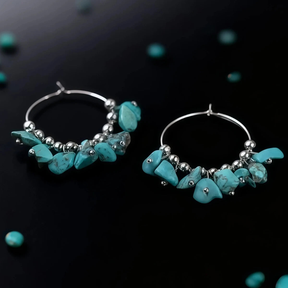 Turquoise hoop earrings with silver beads on a black background