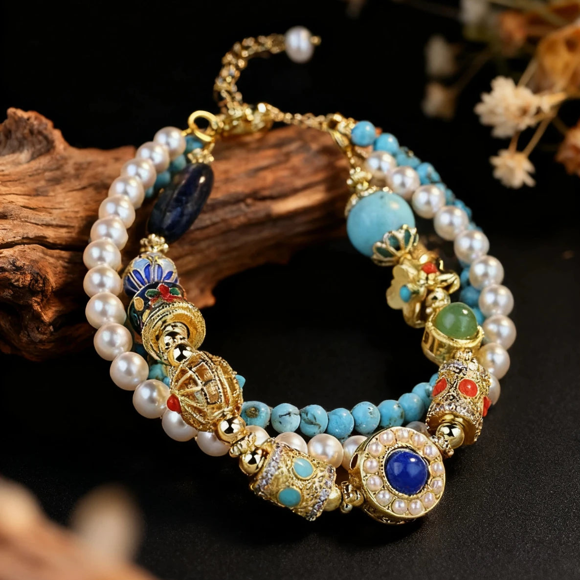 The Triple Celestial Flow Bracelet resting on dark textured wood. It features three strands of pearls, turquoise, and lapis lazuli with gold Tibetan charms, showcasing a rustic and spiritual aesthetic.