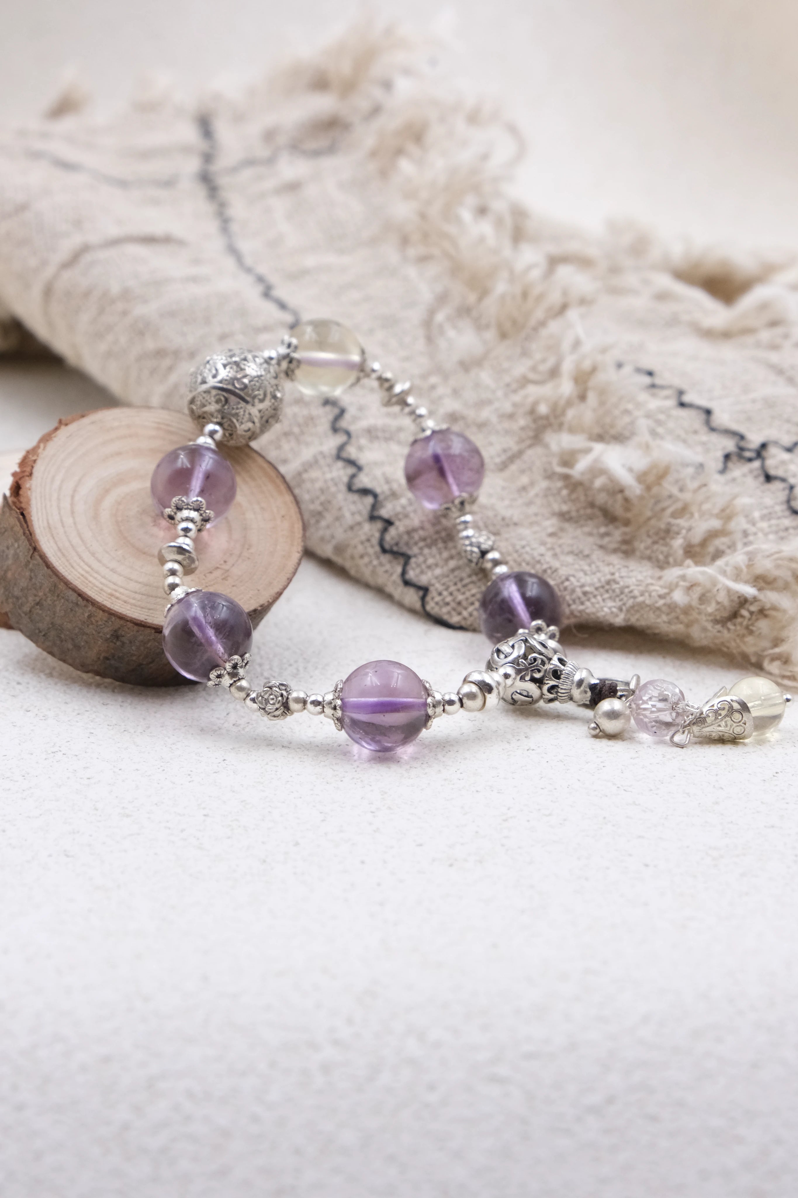 Vajra Bell Crystal Energy Beaded bracelet with purple and clear beads on a textured surface