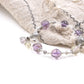 Vajra Bell Crystal Energy Bracelet with purple and white beads on a textured fabric background