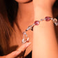Close-up of a hand wearing a Vajra Bell Crystal Energy bracelet with purple and clear beads.