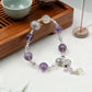 Bracelet with purple beads and silver accents on a wooden tray with tea cup and incense.