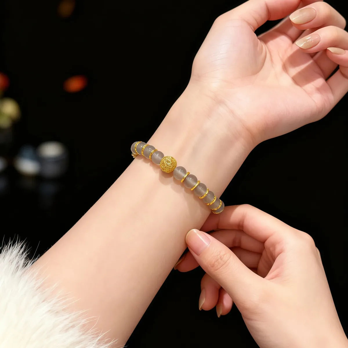 Close-up of a hand wearing a Gray Agate Fortune Bracelet with a dark background