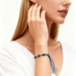 Woman wearing a blue beaded bracelet with tassels on a white background
