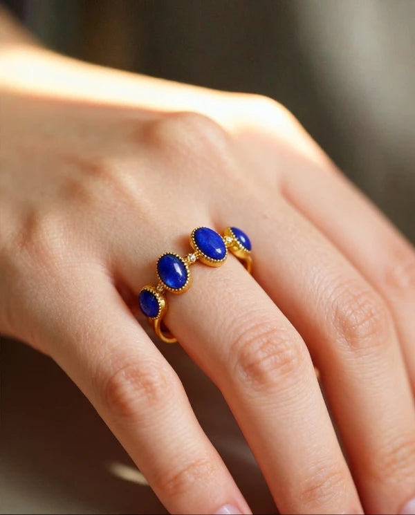 Tibetan lapis lazuli open ring on a person's finger against a blurred background