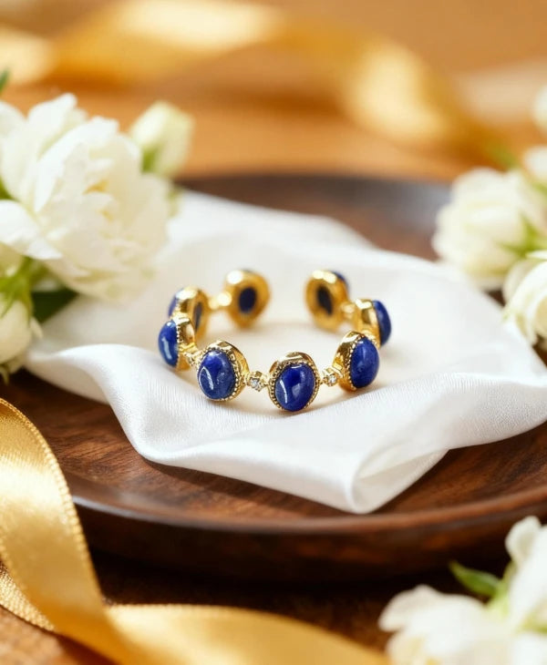 Gold and blue ring on a white napkin with white flowers and gold ribbon