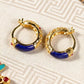 Vintage gold hoop earrings with lapis lazuli and red gem accents, featuring intricate carvings and spiritual oriental design on patterned fabric background.