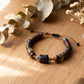 Bracelet with natural beads on a wooden surface with leaves and stones