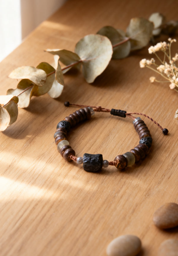 Bracelet with natural beads on a wooden surface with leaves and stones