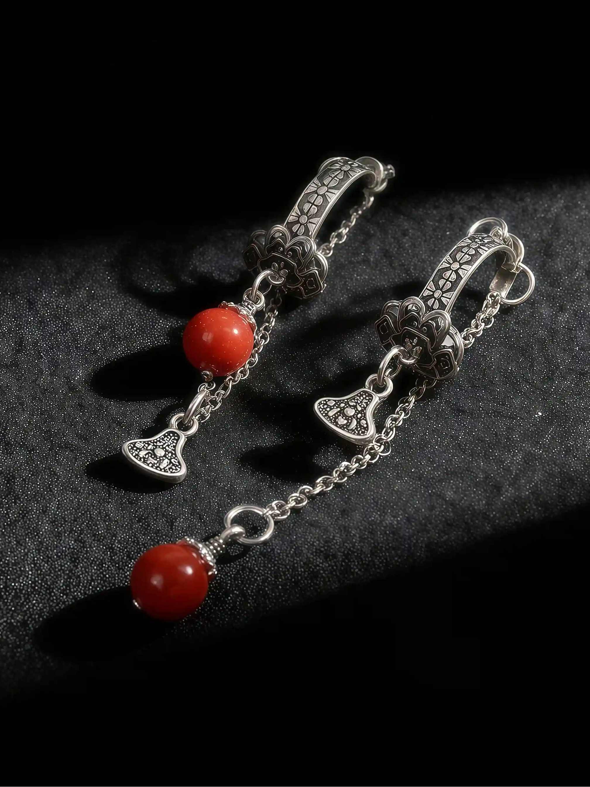 Silver earrings with red beads on a dark background